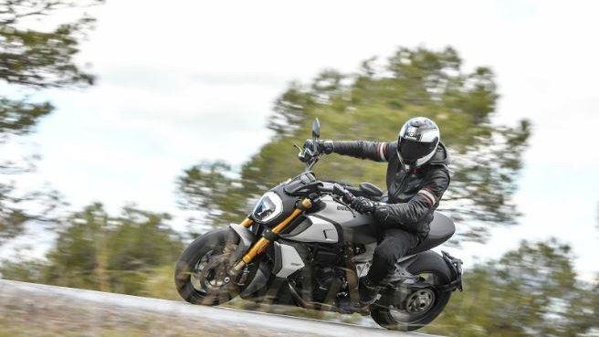 A black, white and gold 2019 Ducati Diavel 1260S being ridden on a country road